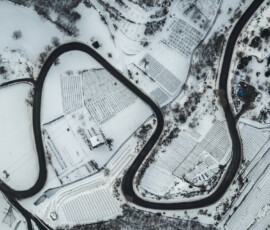 un velo di neve evidenzia le vigne di Charvensod mentre il nero dell'asfalto trasforma la strada in un serpente sinuoso che addomestica il pendio appiattito dalla visuale dalla mongolfiera