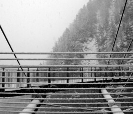 La foto richiama l'apertura di una finestra su un paesaggio invernale. Le linee orizzontali e oblique si intrecciano con armonia. Lo sfondo con gli alberi ritti sulla roccia da forza al contesto ambientale